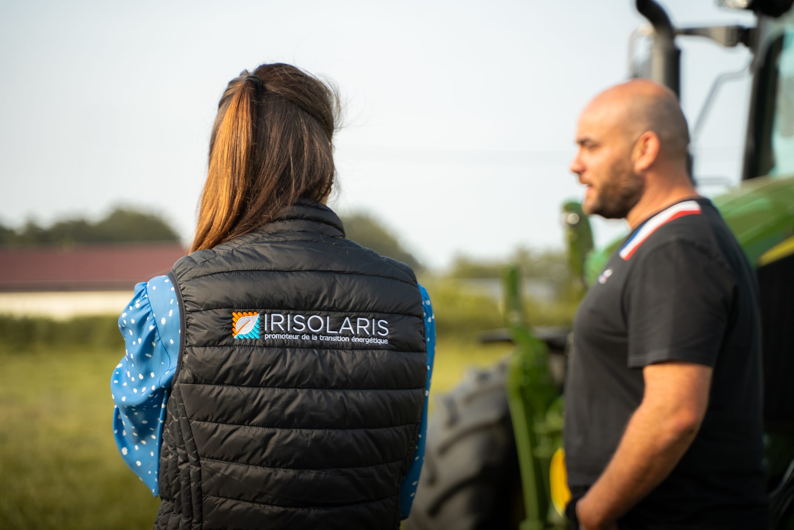 Deux personnes près d’un tracteur, dont une portant un gilet IRISOLARIS.