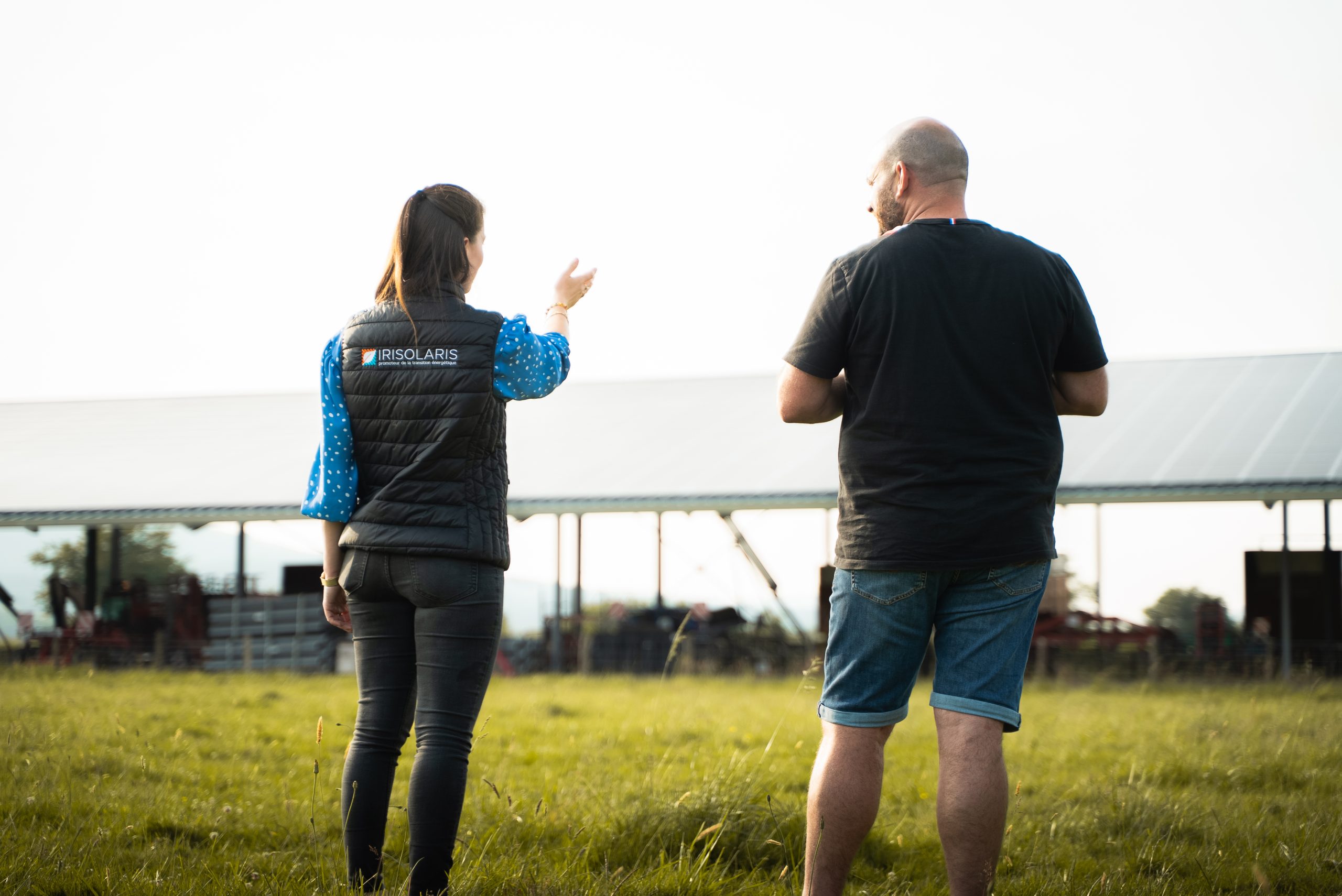 Collaboratrice Irisolaris et un client de dos face à un bâtiment agricole